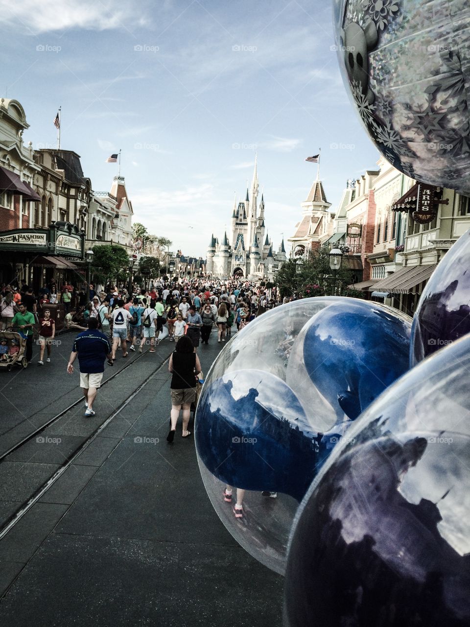 Main Street Disney World. Strolling past Main Street stores, Mickey Mouse shaped balloons, headed toward Cinderella's castle. 