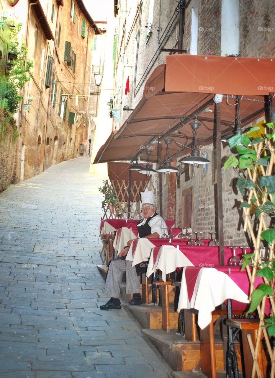 Chef of the day. A chef takes s break at an outdoor table before the dinner crowd starts in sienna 