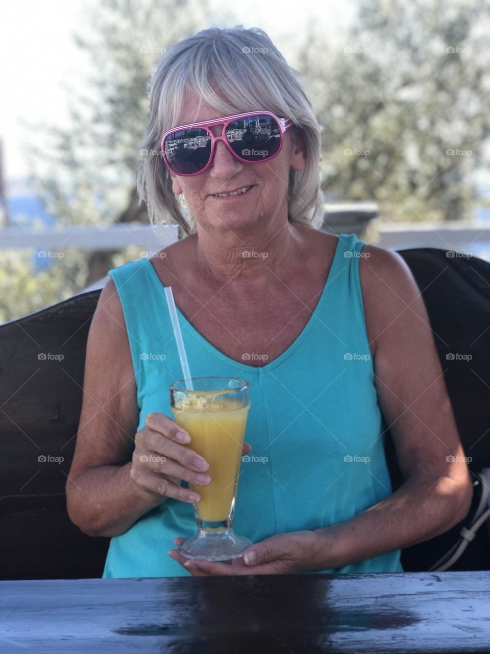 Female wearing sunglasses, holding a glass of fresh orange juice, drink, smiling, happy