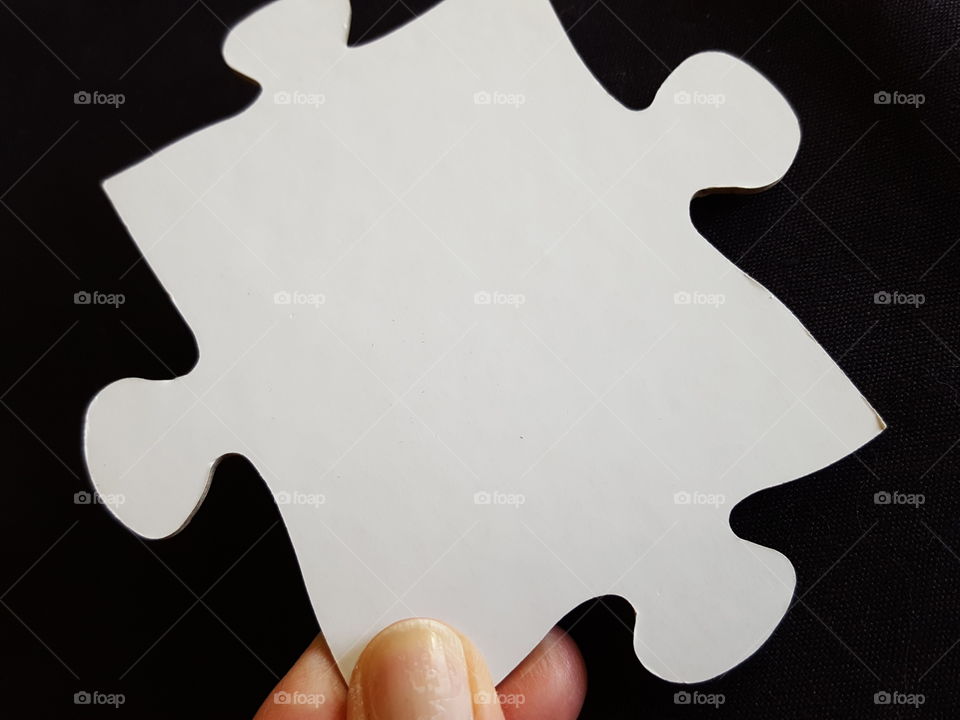 Human finger holding a puzzle piece