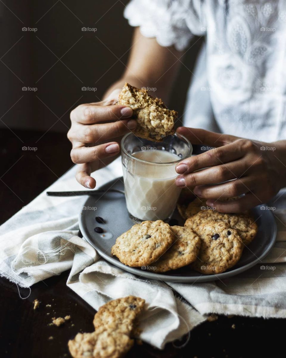 A girl eating oatmeal cookies with milk