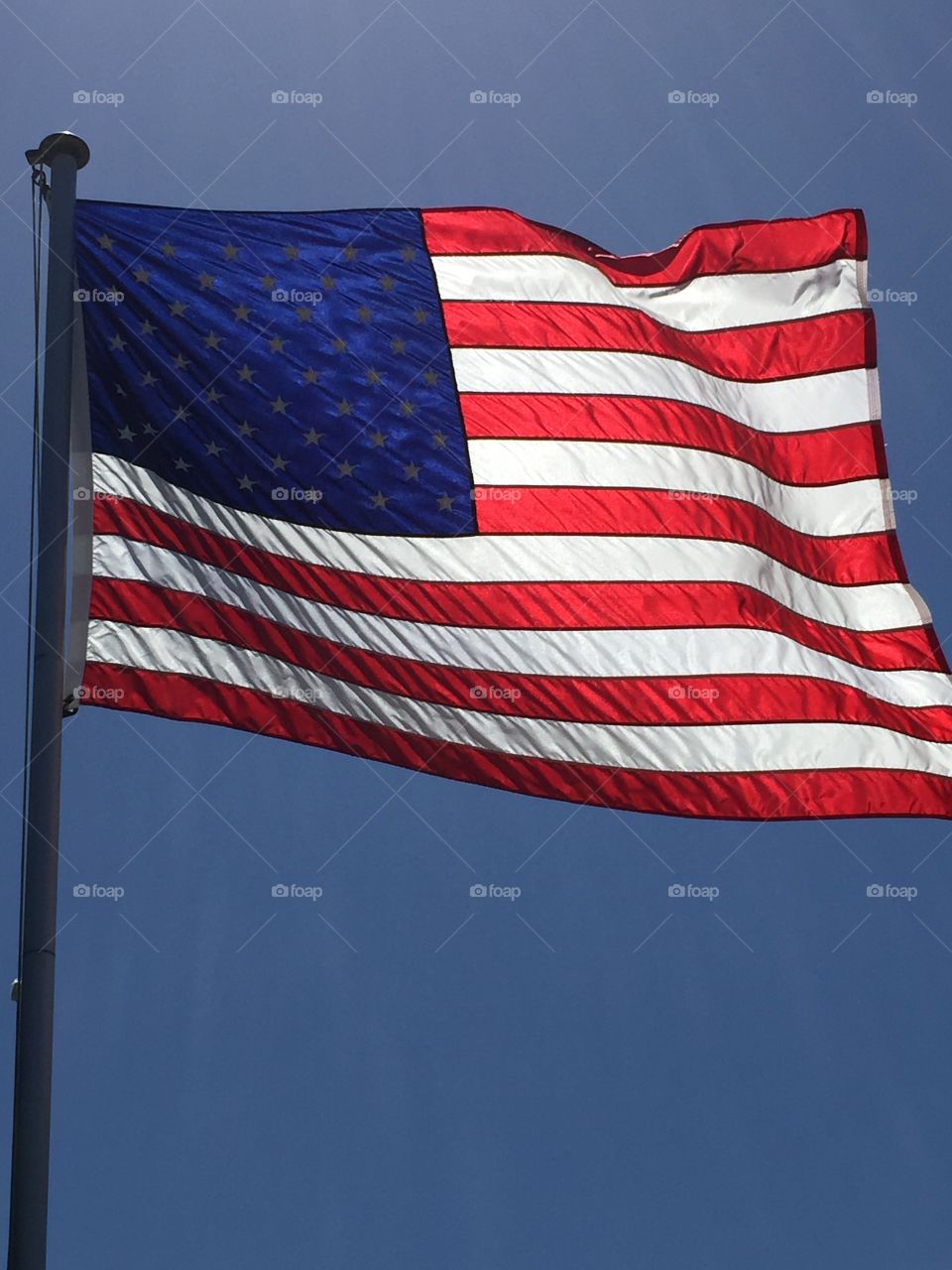 American flag. American flag blowing in the wind backlit