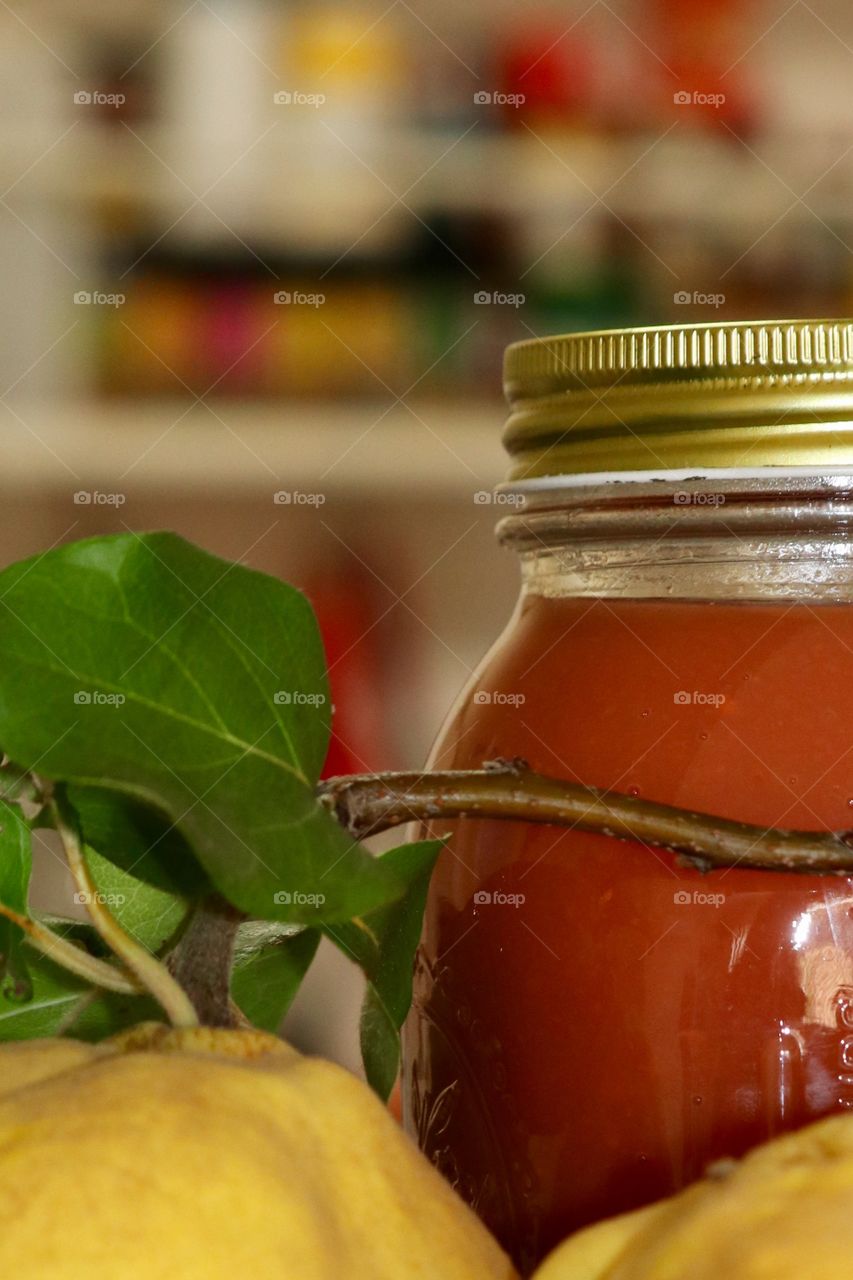 Closeup partial view jar of freshly made country fresh quince fruit preserves; blurred kitchen background 