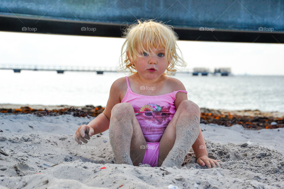 Little girl playing in the sand at Ribban beach in Malmö Sweden.