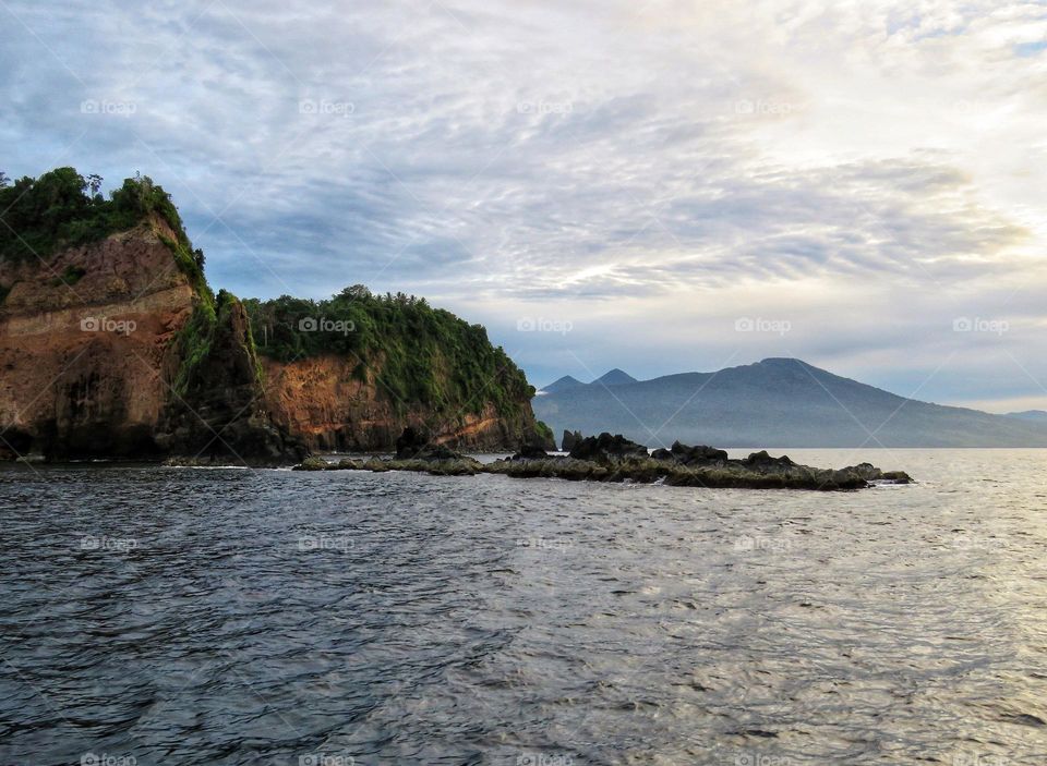 Natural scenery, cliffs and coral beaches against the backdrop of beautiful mountain silhouettes and cloud formations.