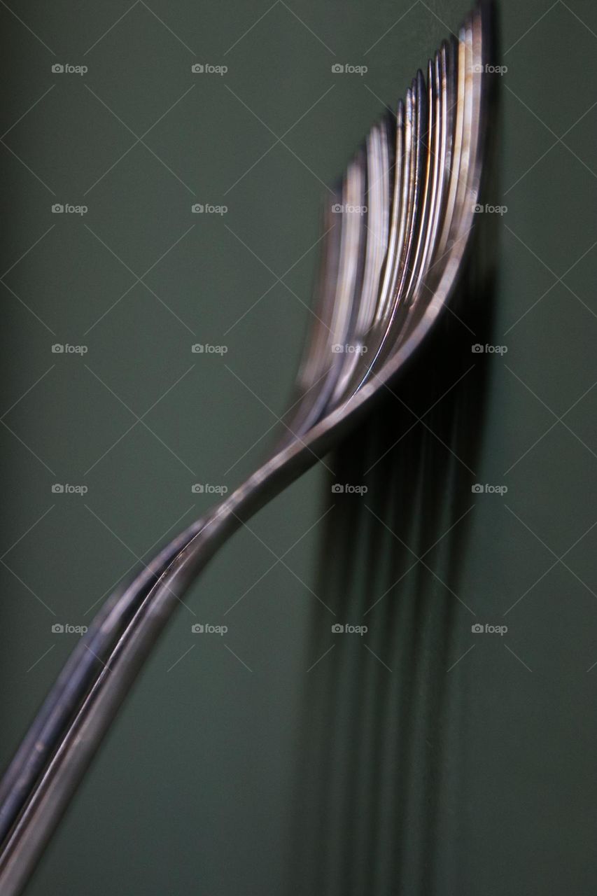 Close up of silver forks standing on green wall 