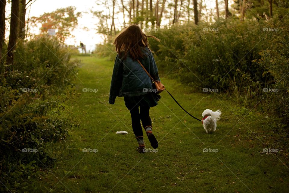 Girl walking her puppy into a forest, dusk