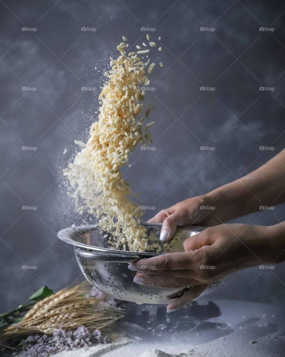 A chef's uniform sips the dough for a honey cake in the kitchen in a solid background behind Flowers A flour on the table