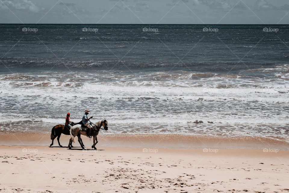 Men riding on the deserted beach