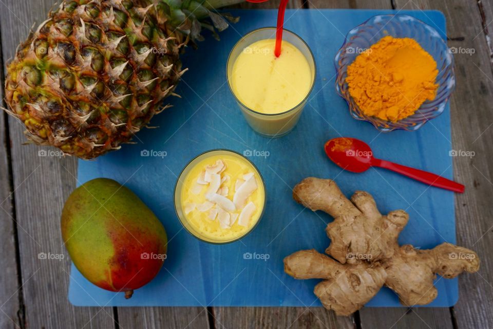 Mango pineapple turmeric ginger smoothies with red spoon
