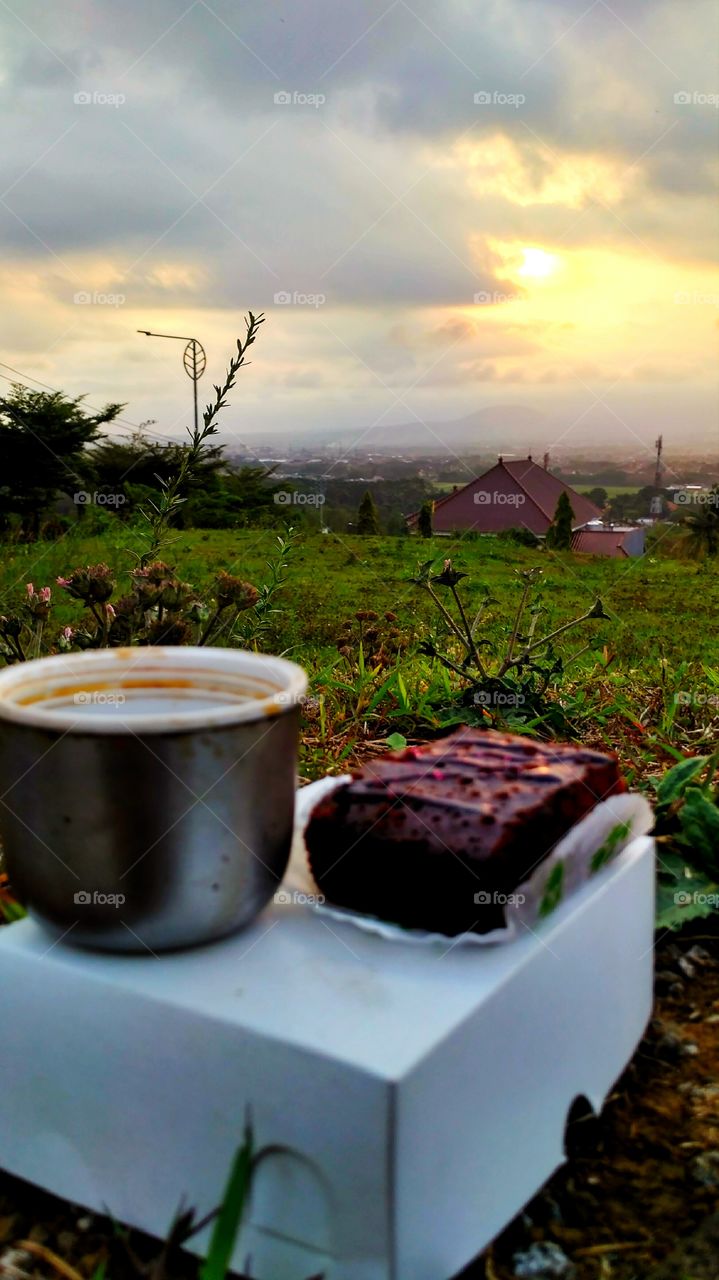 having sunset moment with a cup of coffee and a piece of cake