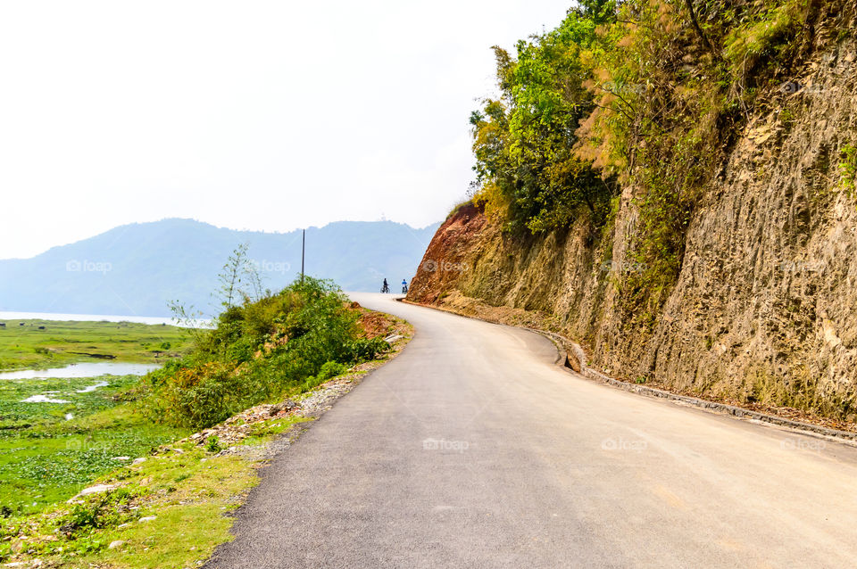 Photograph of empty road with hill in surrounding near Pokhara Lake at Kathmandu Nepal. Snap in portrait, landscape, wide screen style. Vintage film look. Vacation Freedom, Simplicity Concept.