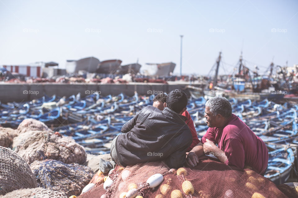 Men relax and watch the boats in the marina of Essaouira 