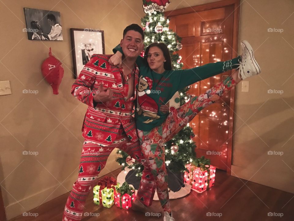 Couple posing in front of decorative Christmas tree