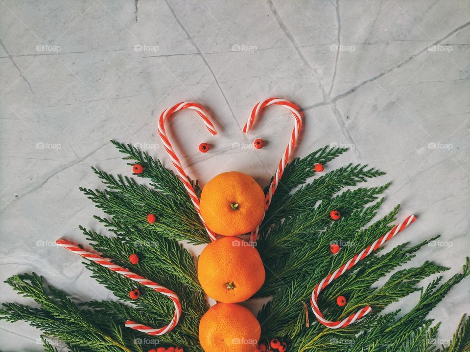 Christmas and New Year background with spruce branch, candies, decorations and tangerines Flat lay. Top view.