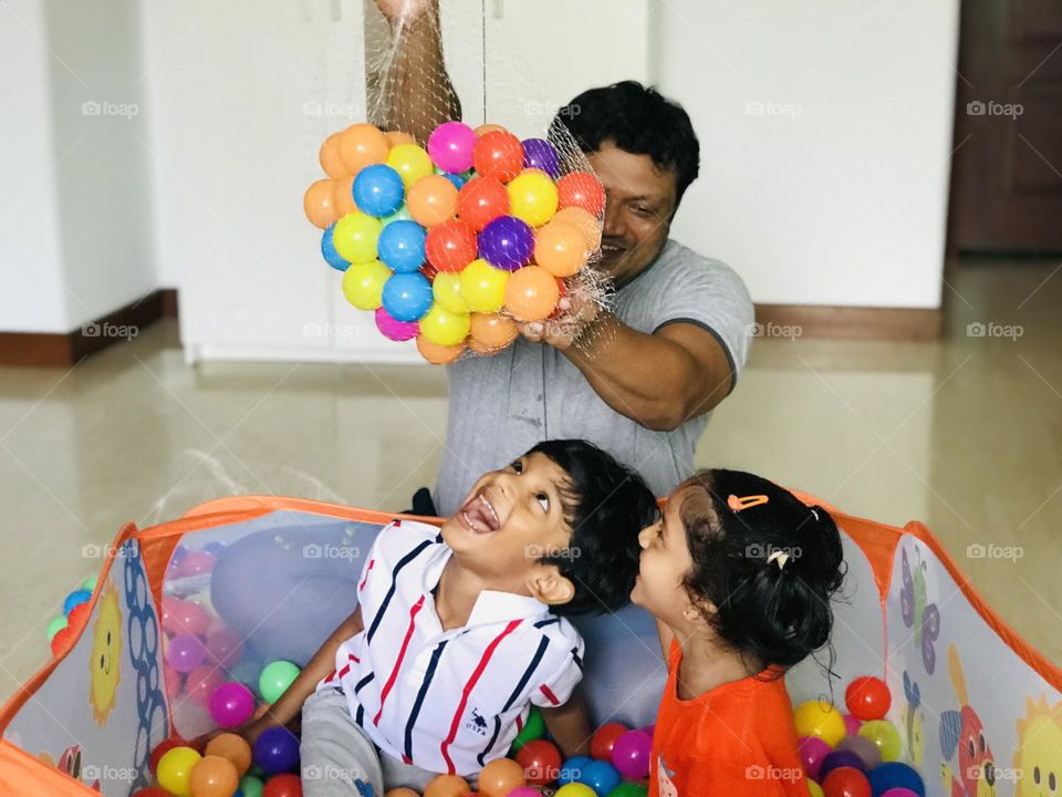 Kids have a great fun with father by playing in ball pit at house 