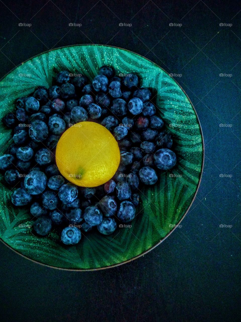 In this picture is blueberries and two lemon on a black table😊
.
