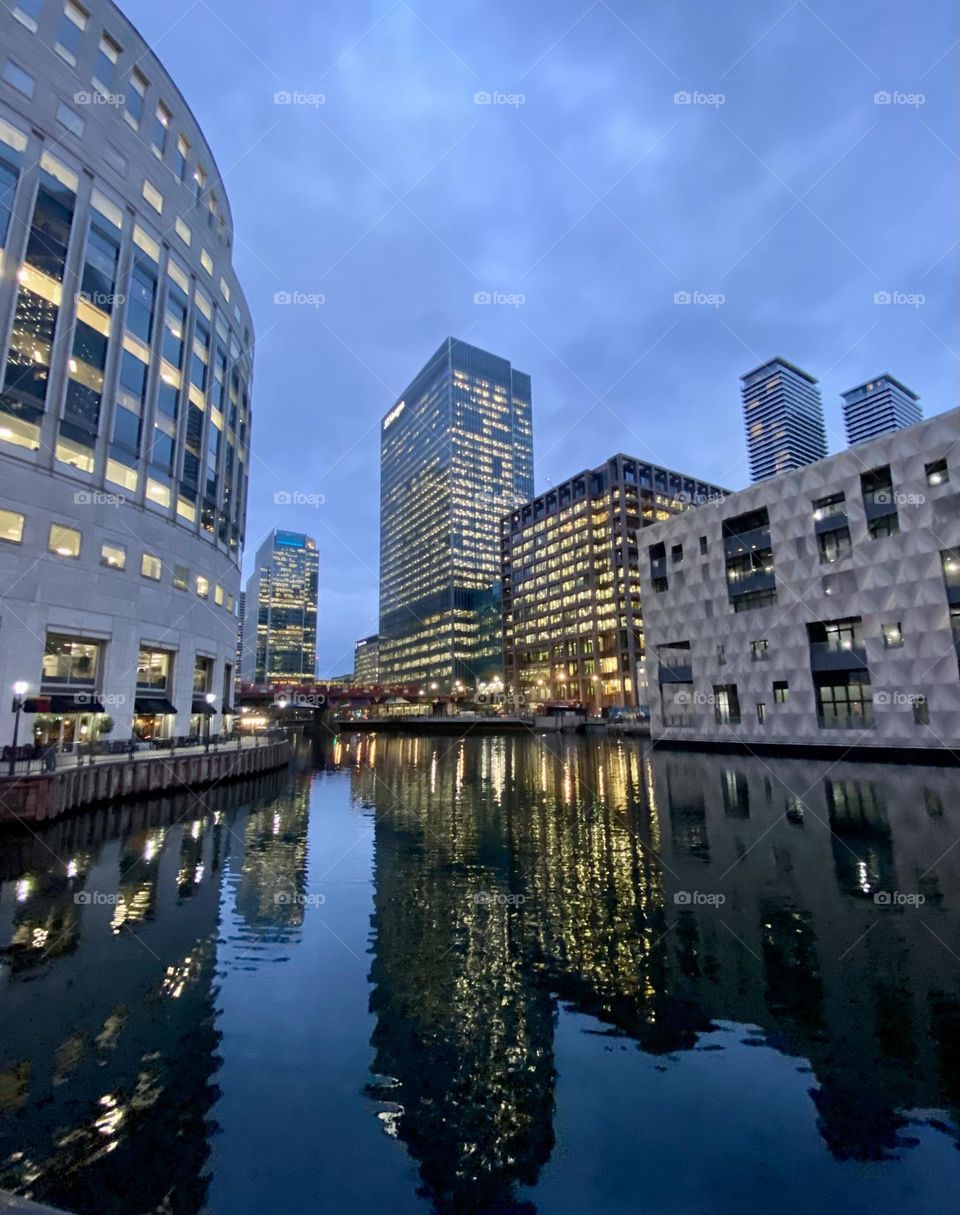 Buildings with illuminated windows during evening and reflection at water