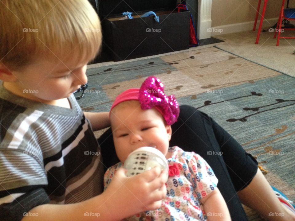 Brother feeding milk to his little sister