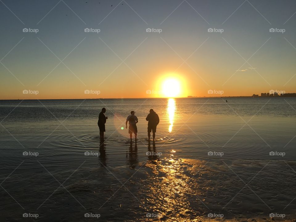 Silhouettes in the ocean at sunset 