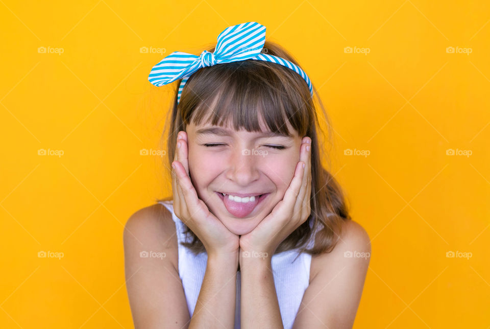 Little girl with funny faces against yellow background