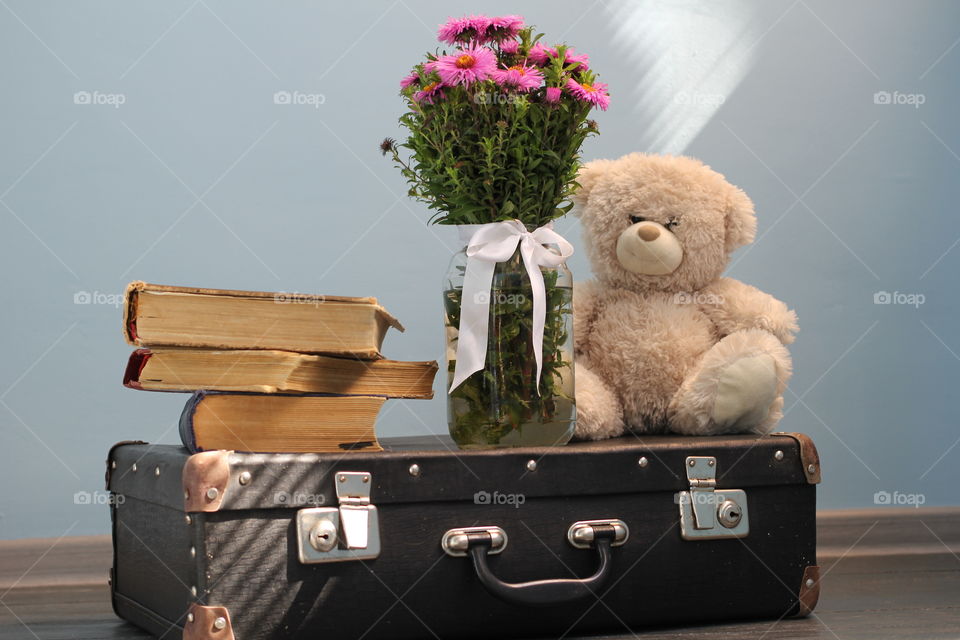 Still life: an old suitcase, a teddy bear and a bouquet of flowers