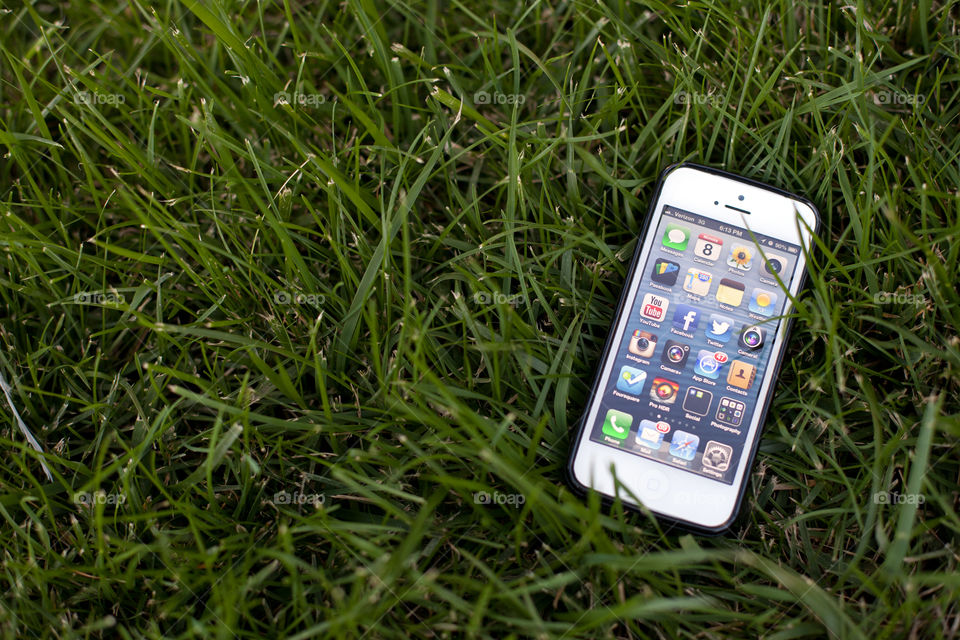 Apple iPhone 5 laying on the grass field isolated 