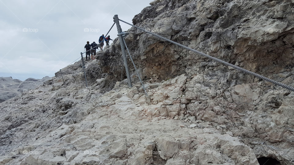Hikers on rocky hiking trail with wire ropes 