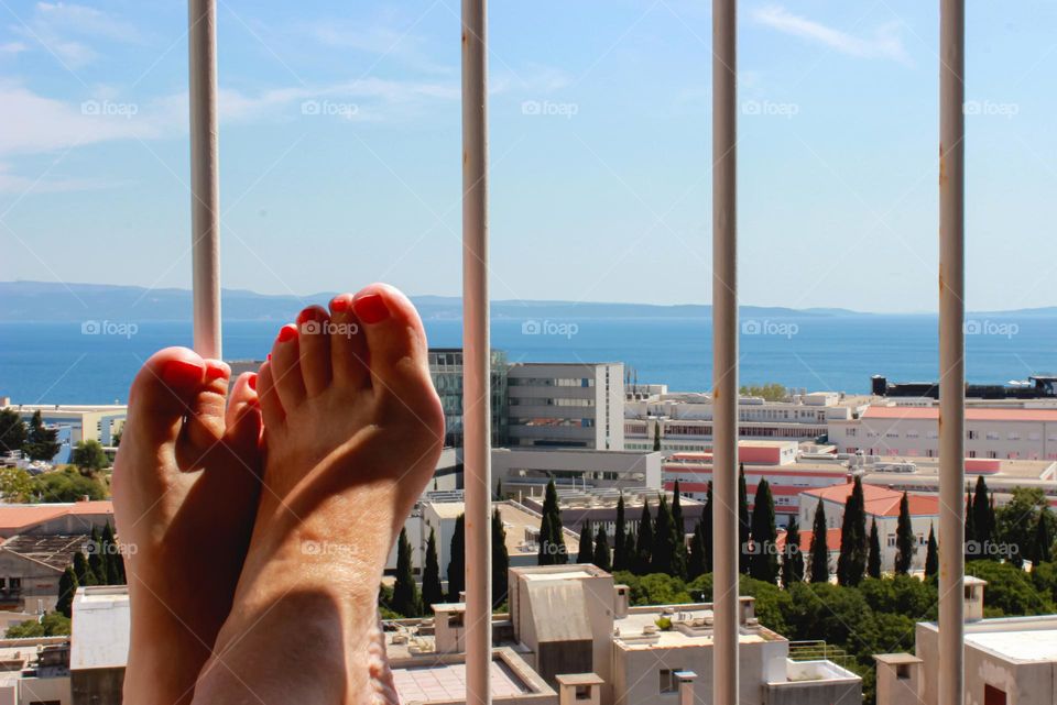 Relaxing with feet on the balcony fence looking at sea and sky