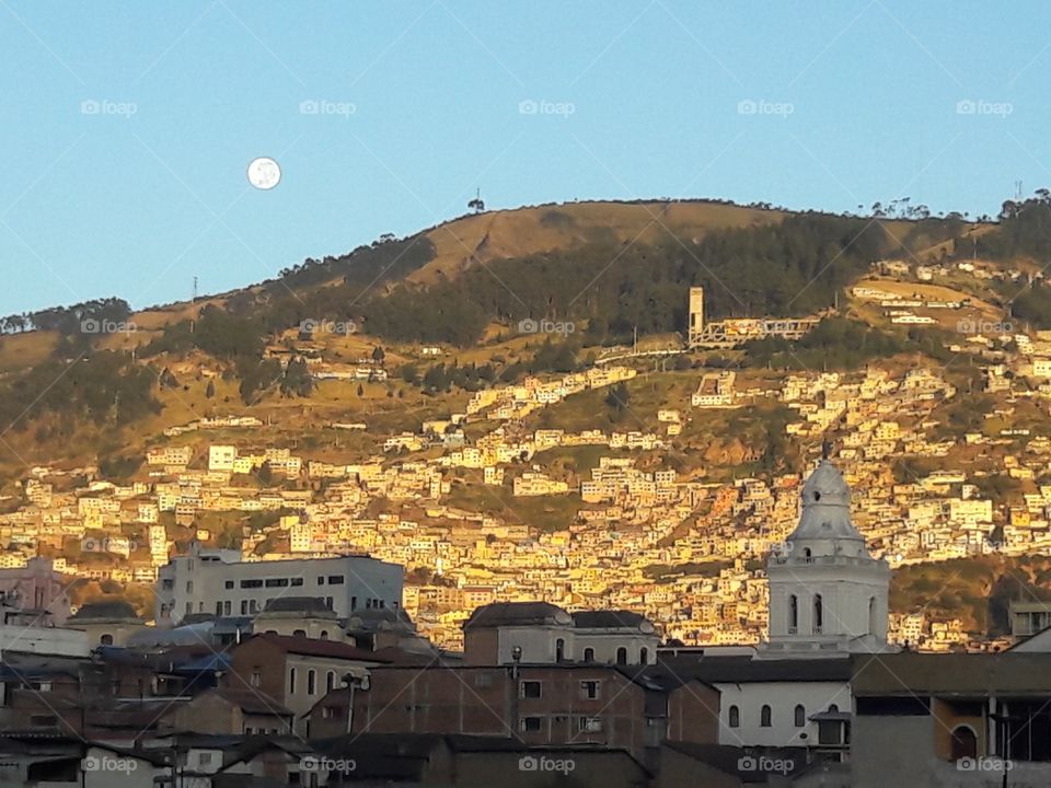 Expansive view of Quito, Ecuador old town with moon 🌒 and hillside neighborhoods