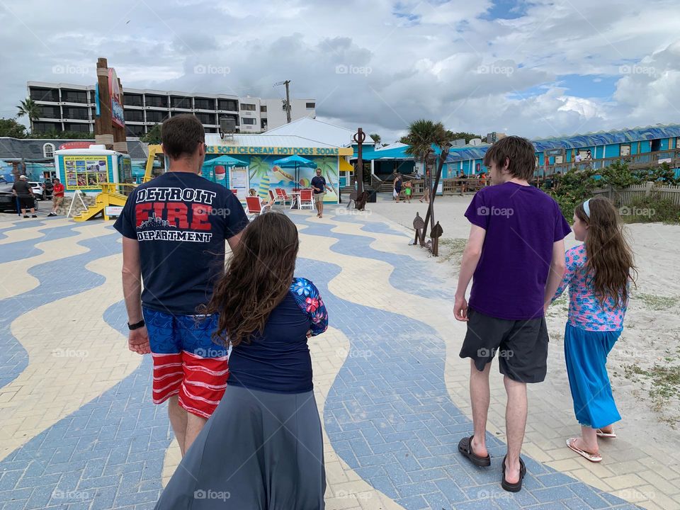 Visiting the visitor touristic pier in Cocoa Beach as a family for the first time in central eastern Florida with many shops, restaurants, business and boutiques at the Atlantic Ocean beach seashore with a crowd.