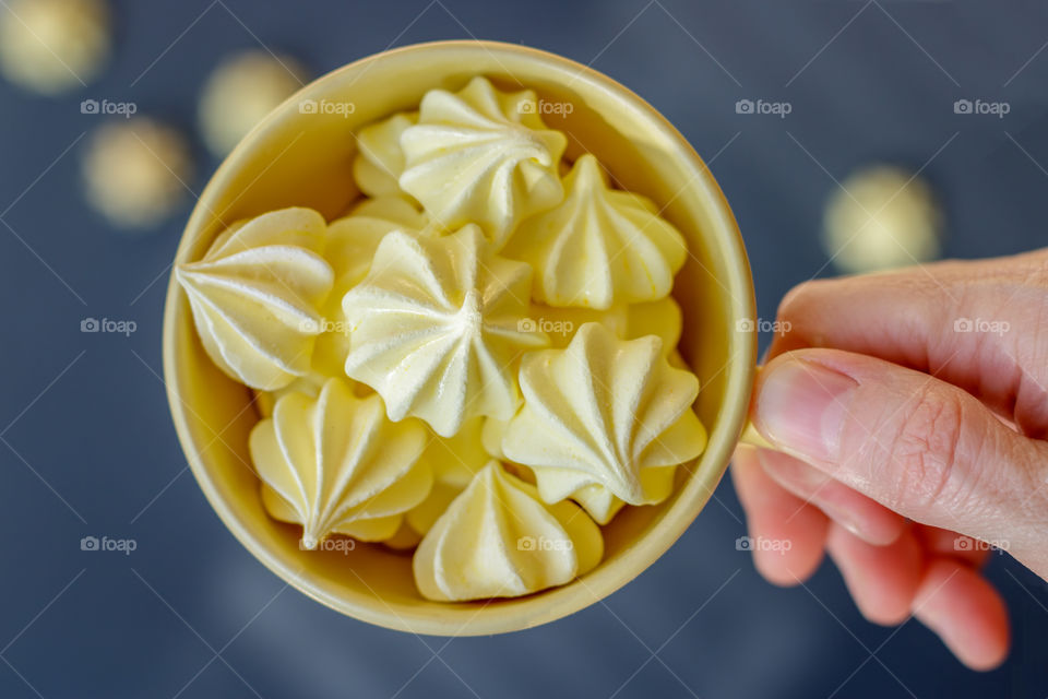 Yellow meringues in yellow cup at gray background. Top view. Abstract image.