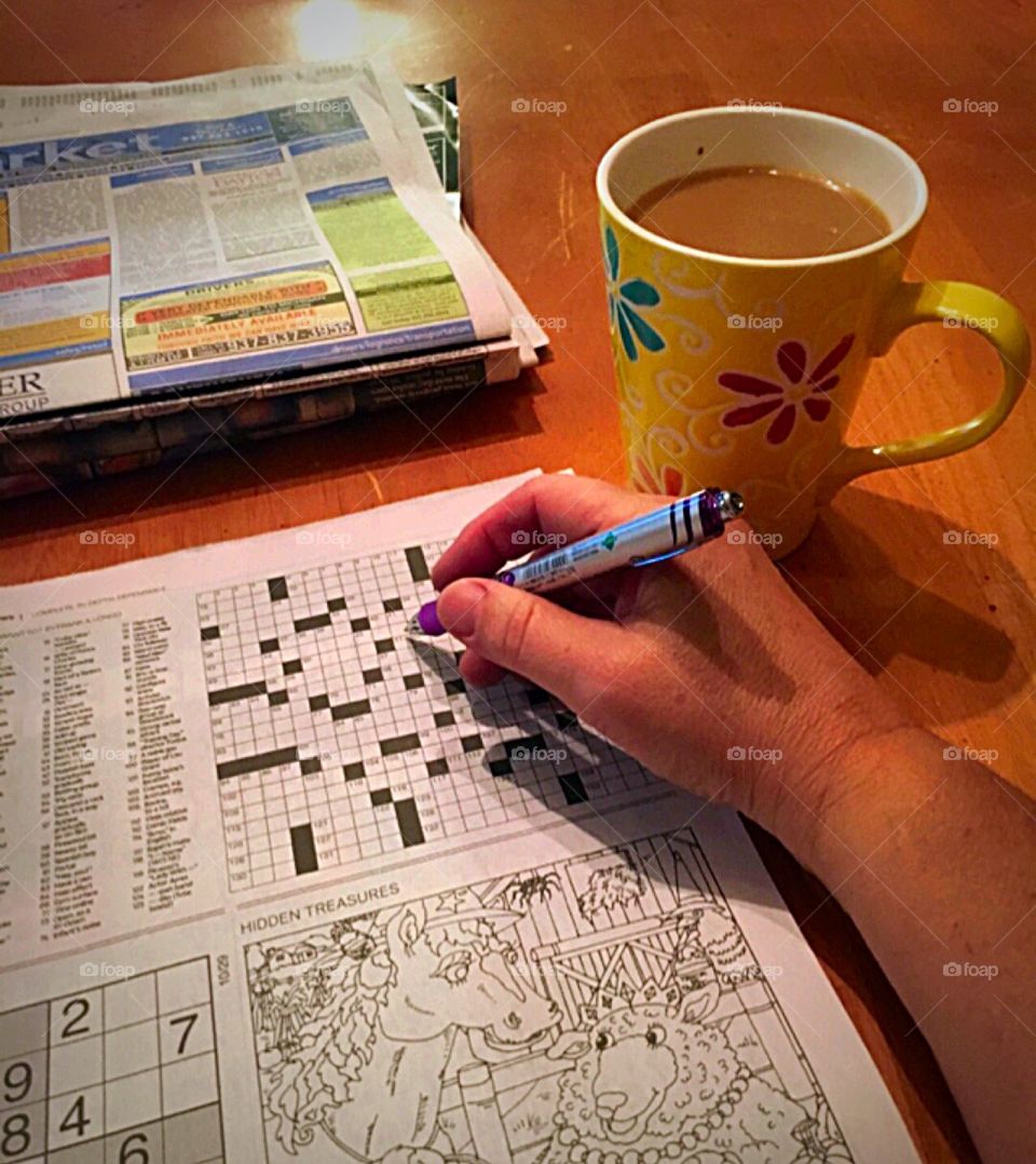 Working crossword puzzle with coffee