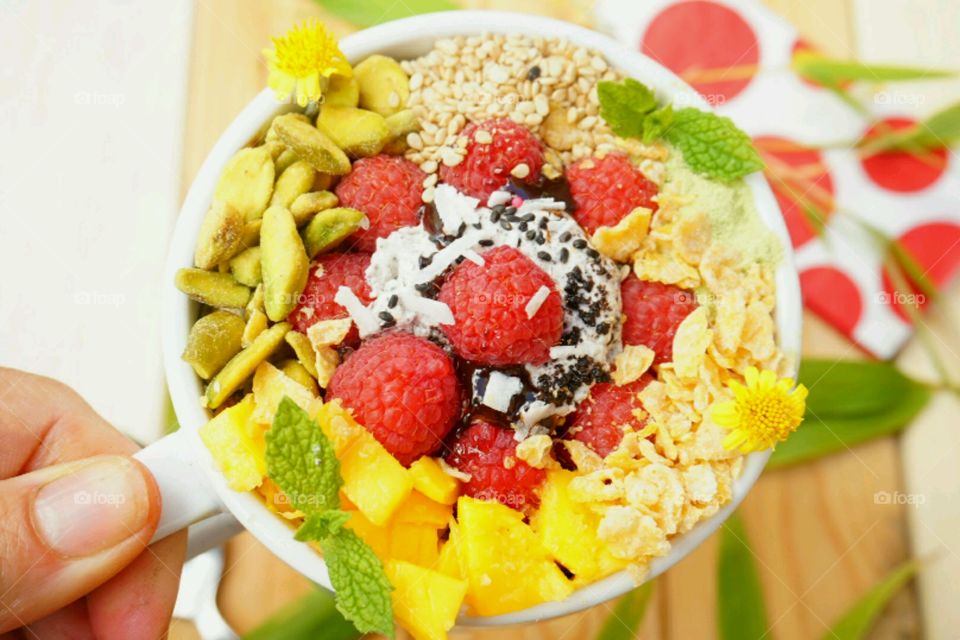 Fresh fruit smoothie bowl - raspberry,  nuts, mangoes,  cereal, seeds, mints