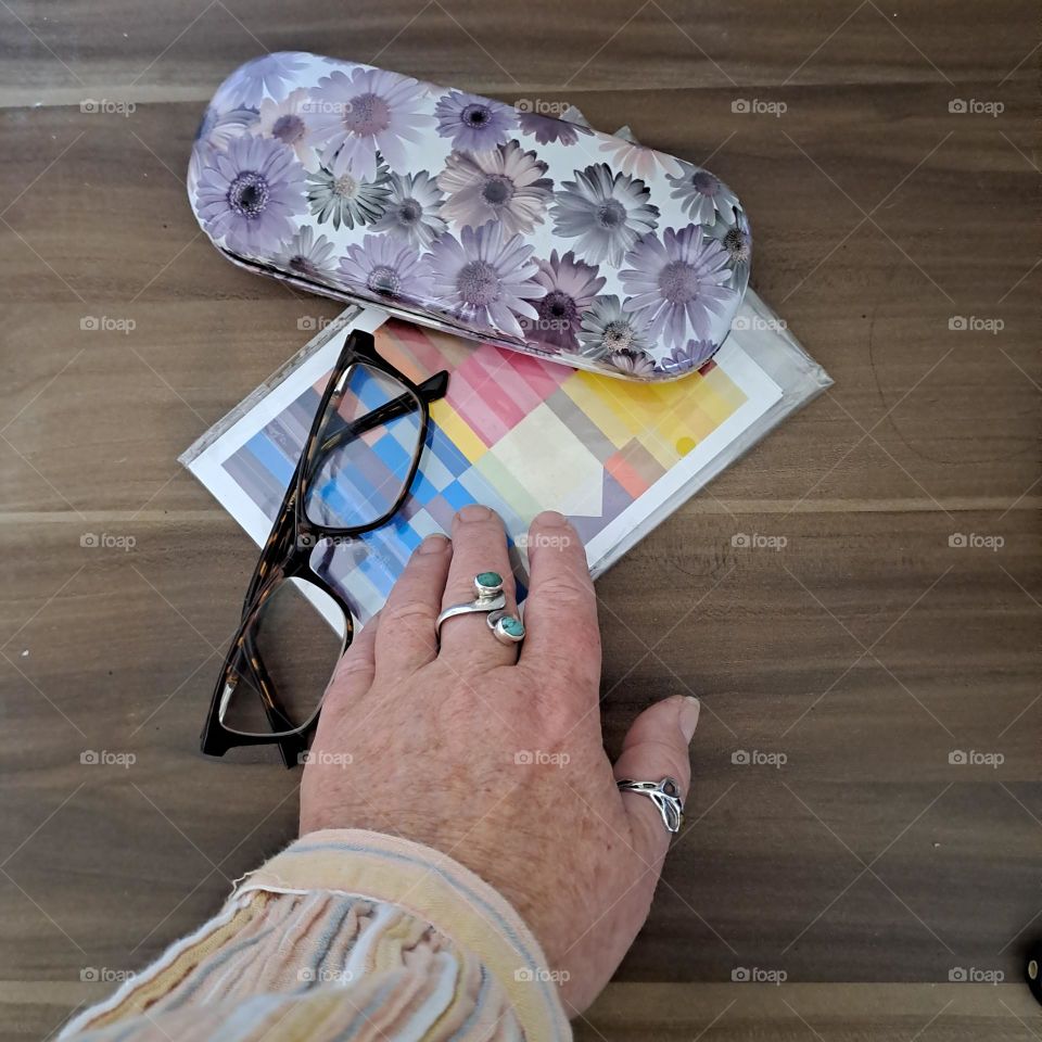 ladies hand shirt sleeve reaching out to pickup accessories from wooden surface