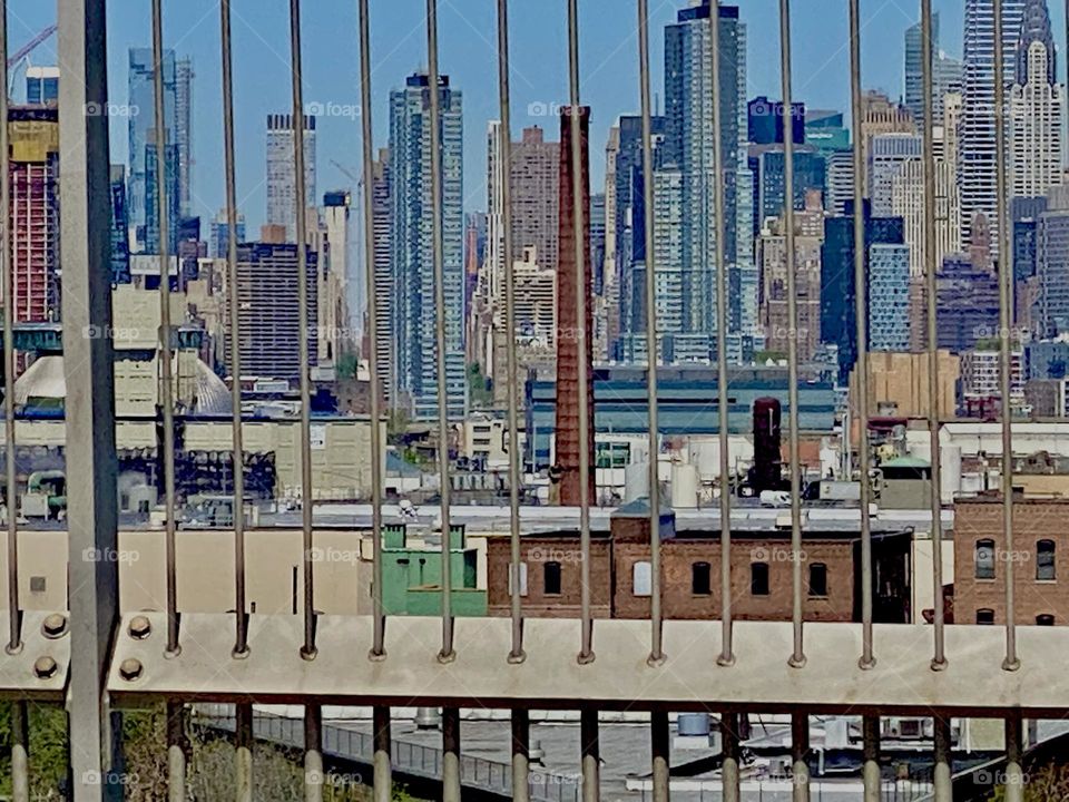 A view through the railing along the „Brooklyn Queens Expressway“ while driving from Long Island City, Queens into Brooklyn, NY on a clear sunny morning in 2022. Manhattan is in the background. Hypnotic Productions