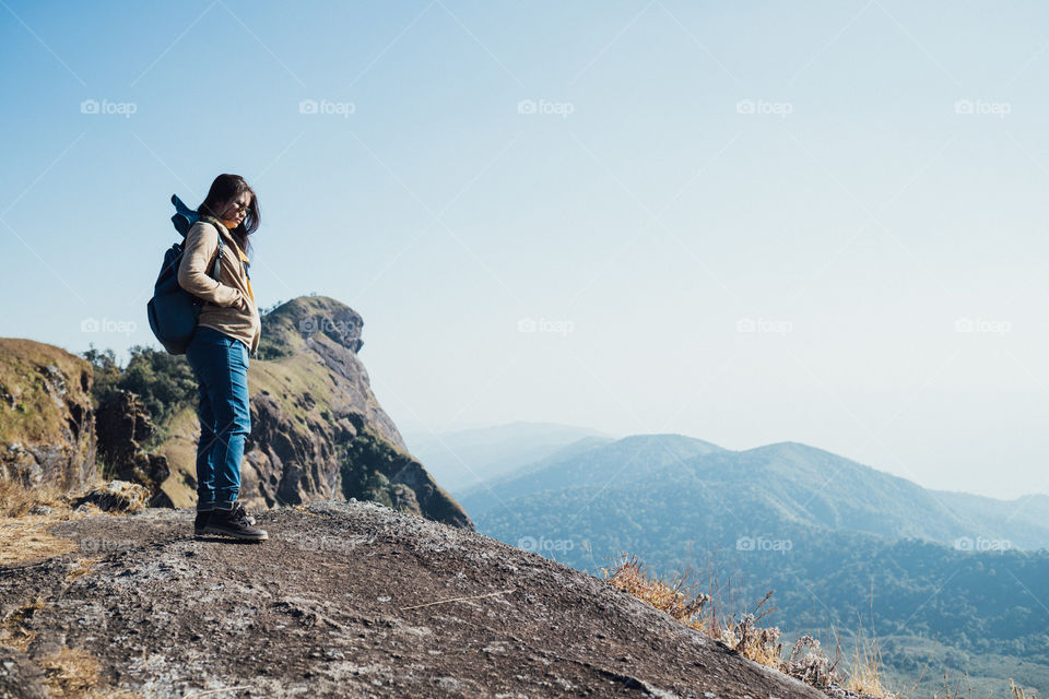 Asian woman standing on the edge of a cliff