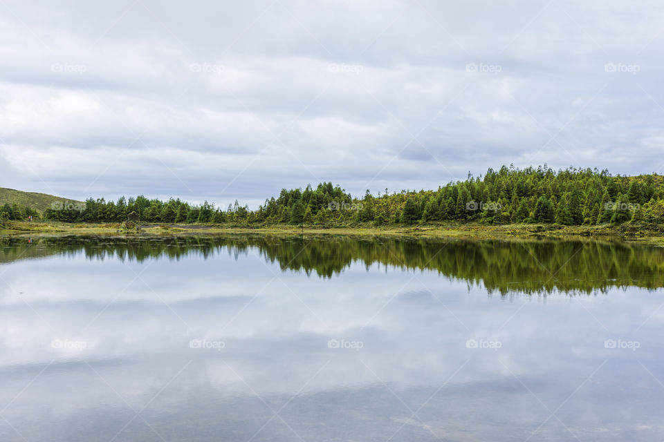 Hiking on the trail of Serra Devassa in Sao Miguel Island, Azores, Portugal. Vulcanic lake, clouds and reflection.