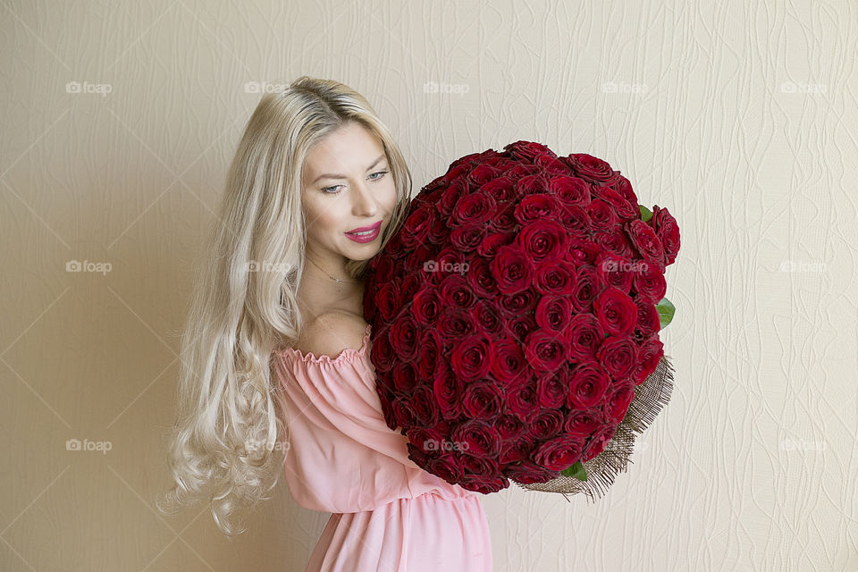 Smiling young woman holding bunch of red rose flowers
