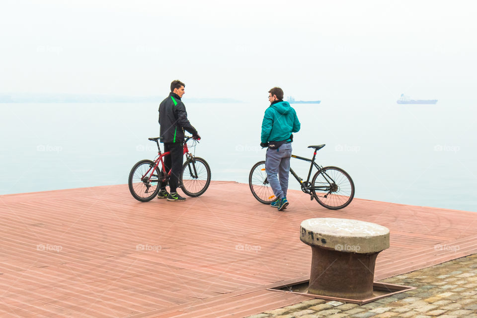 Two Friends With Bikes On The Quay
