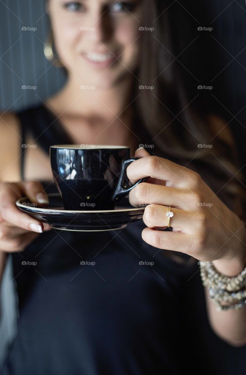 Photo of girl holding coffee mug with engagement ring on
