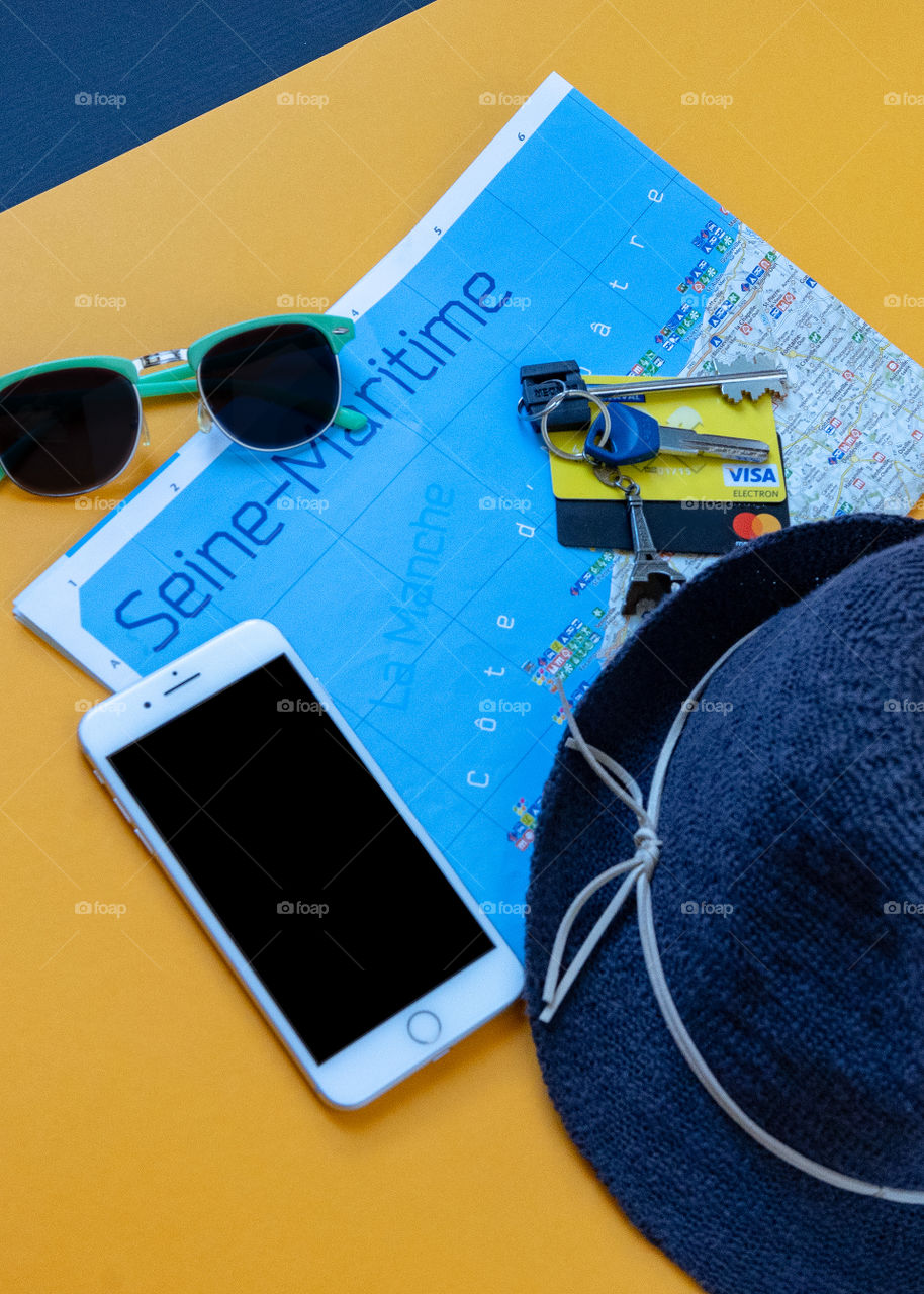 sunglasses, hat, cell phone, keys, map, credit card, things on vacation on a yellow background, top view