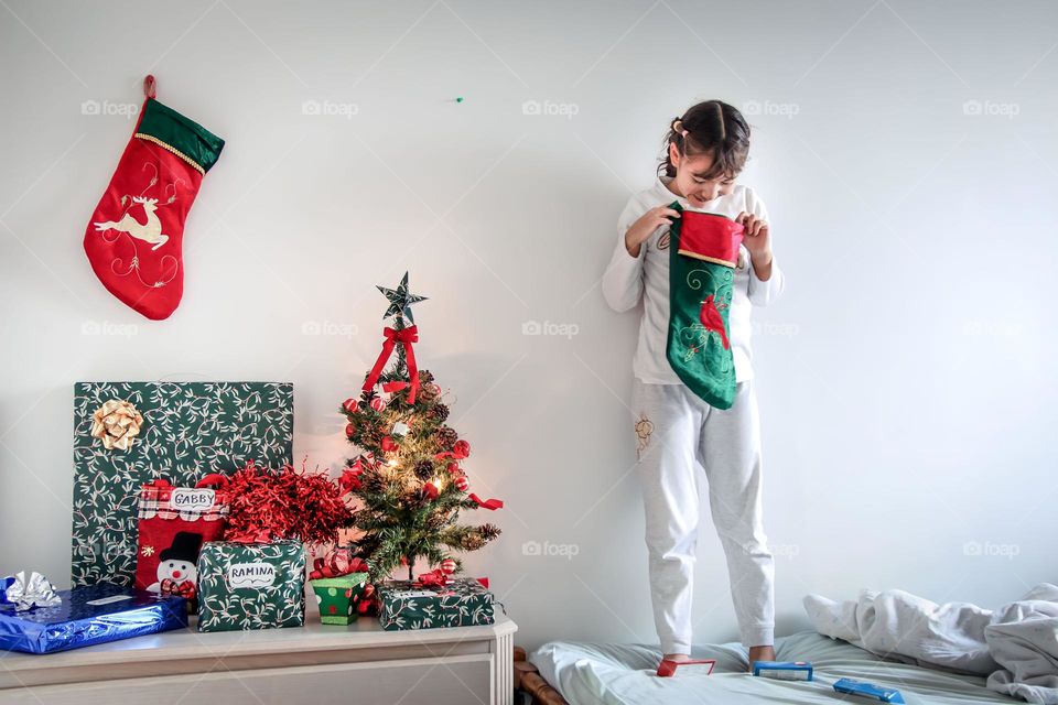 Happy little girl is checking a Christmas sock