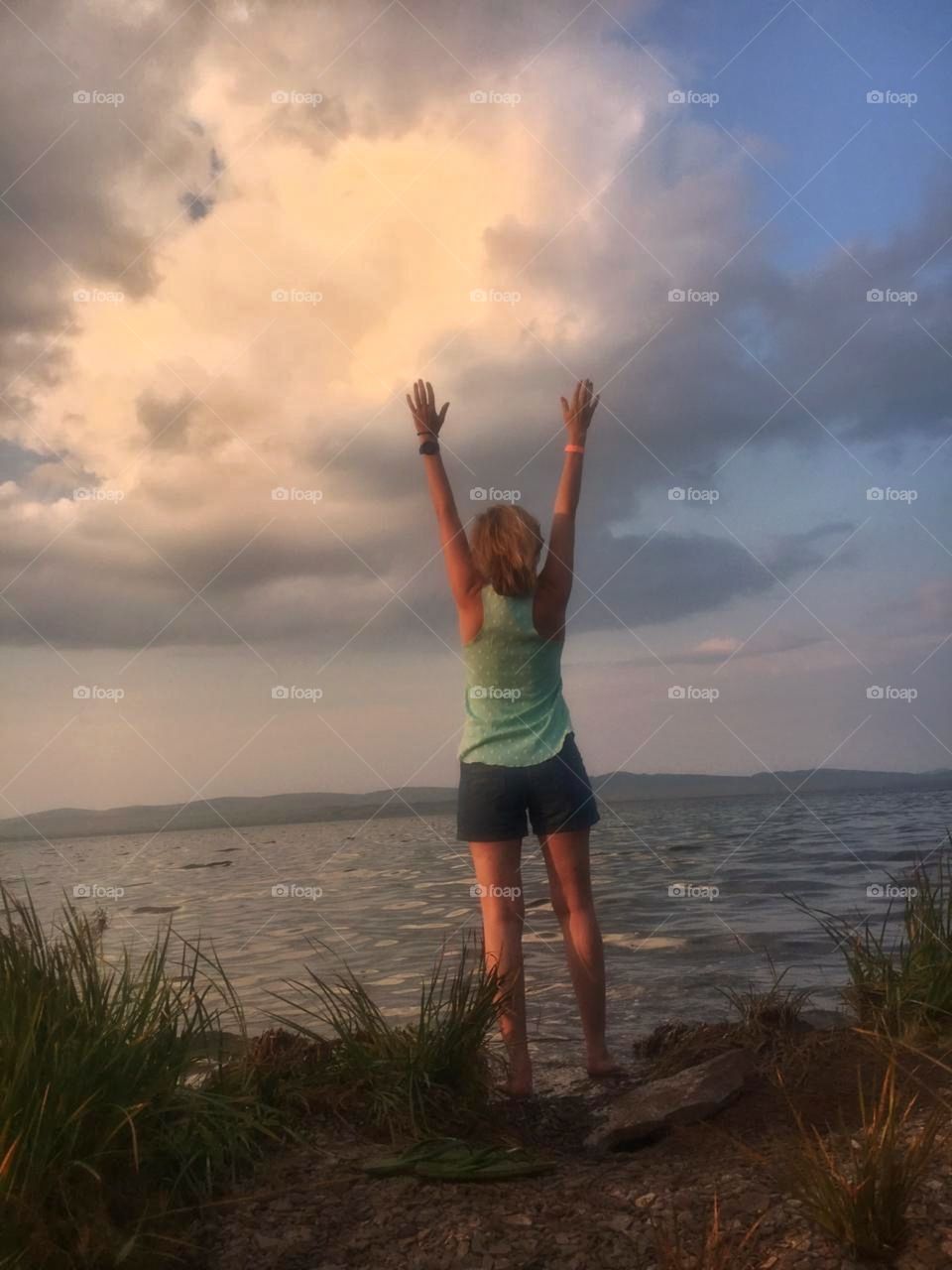 девушка стоит спиной к озеру