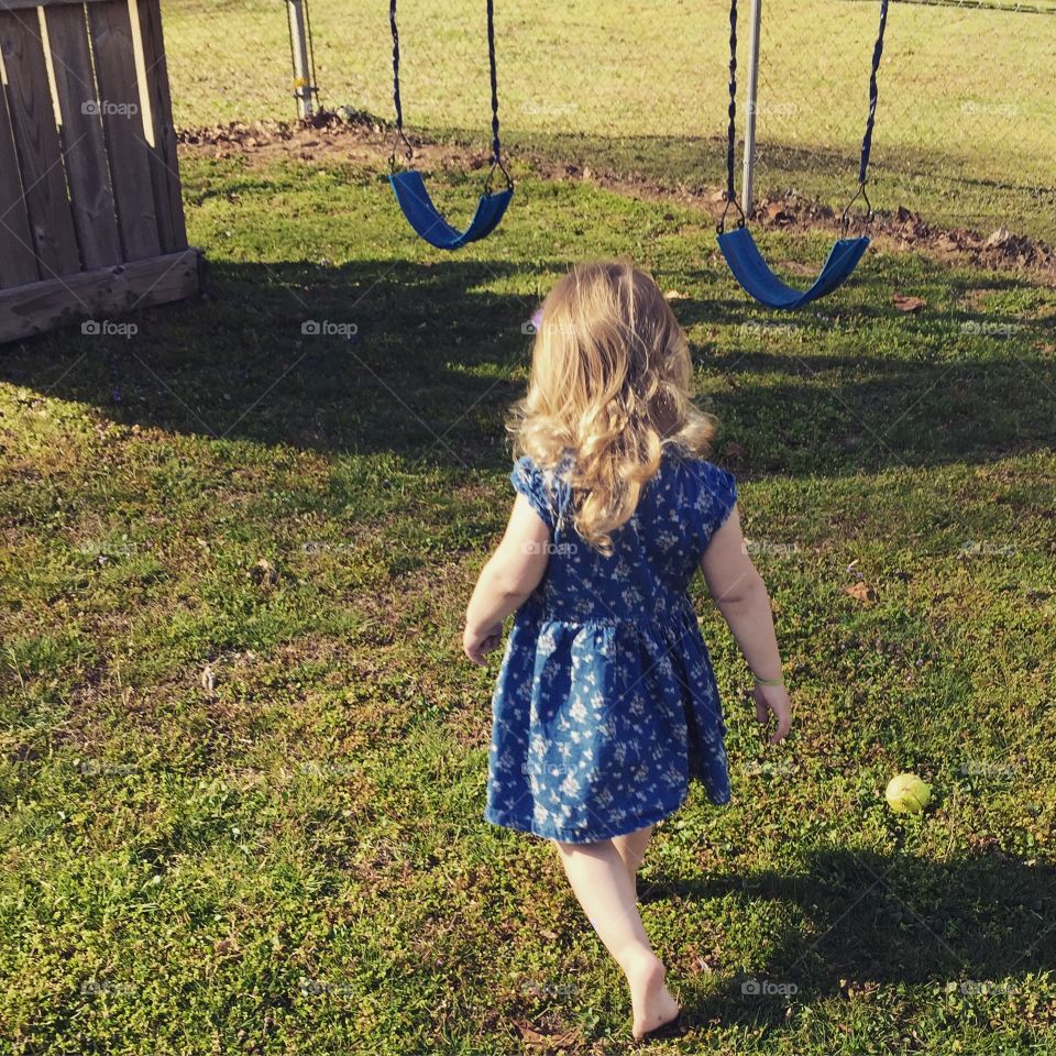 Barefoot little lady goes to swing. Little lady makes her way to a swing set