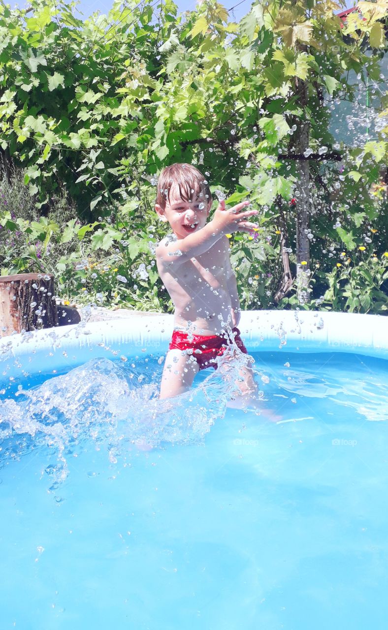 boy in the pool splashing water