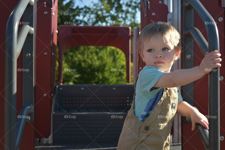 Cute baby boy playing at on jungle gym 