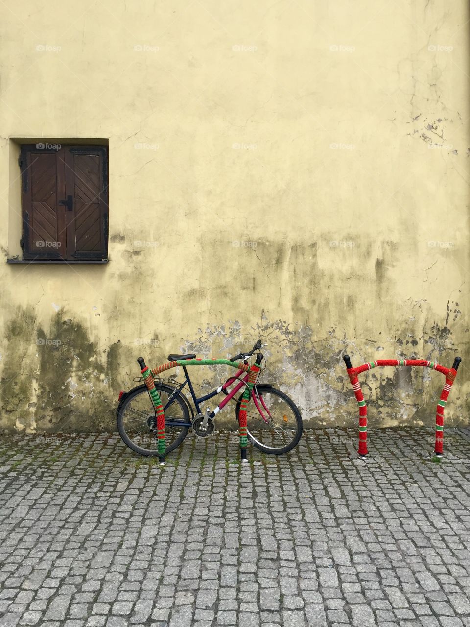 A bicycle parked near a wall with a window in Lublin oldtown