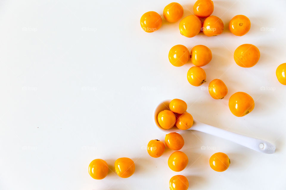 Orange! Fresh gooseberry fruits on a white background with white spoon