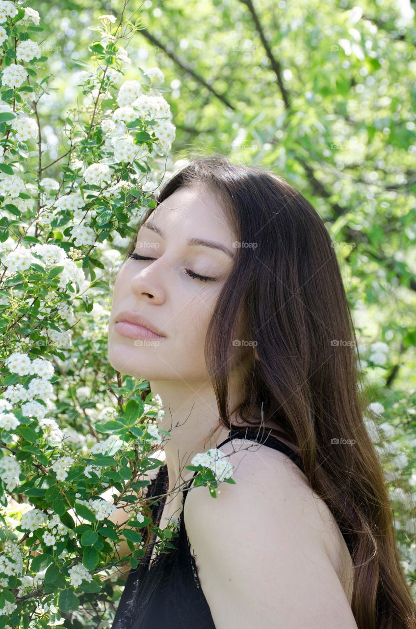 Portrait of a Beautiful Young Girl on Background of Flowers